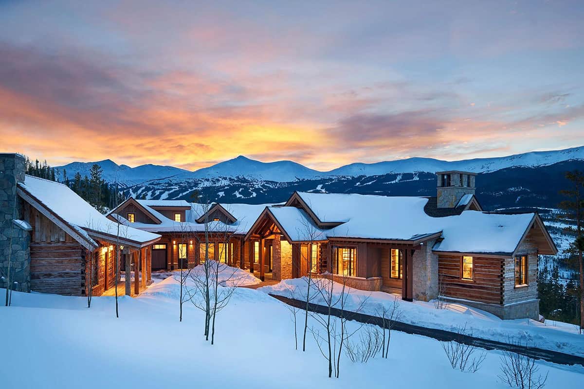 Mountain home at sunset with snowy ski slopes behind