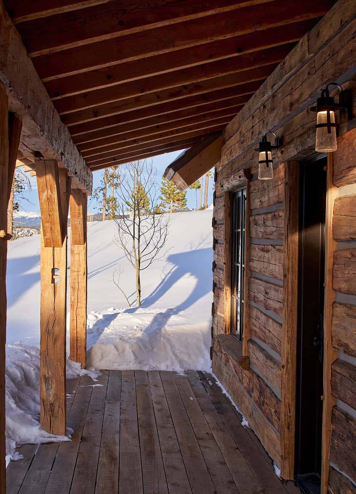 Log cabin porch with timber posts and lantern sconces