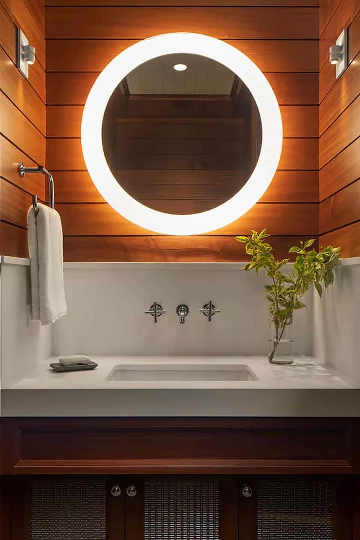 Powder room with glowing round mirror and wood plank walls