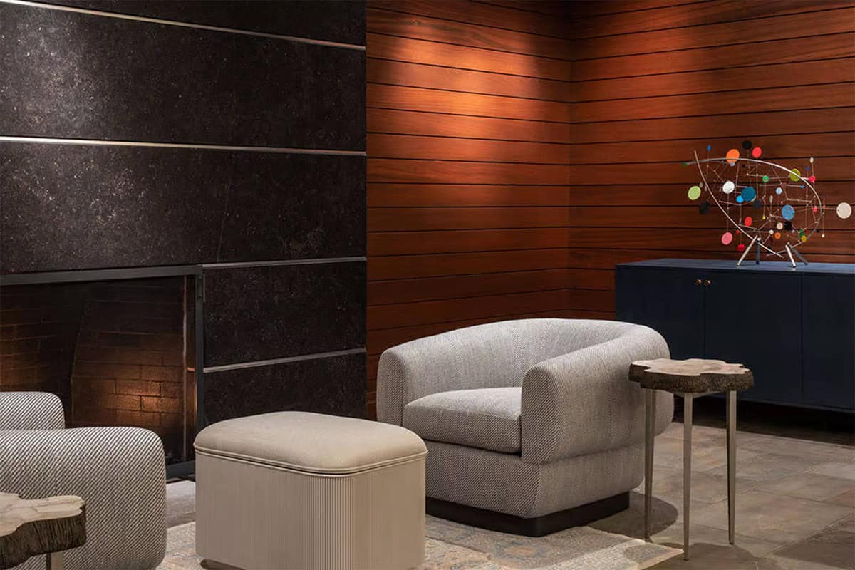 Lounge chair and ottoman by black stone fireplace and wood walls