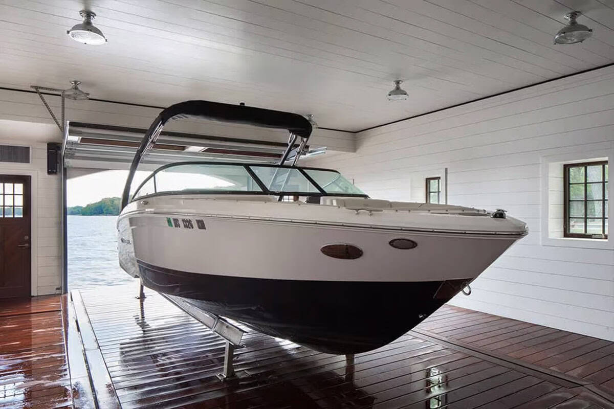Boat on a lift inside a white shiplap boat slip