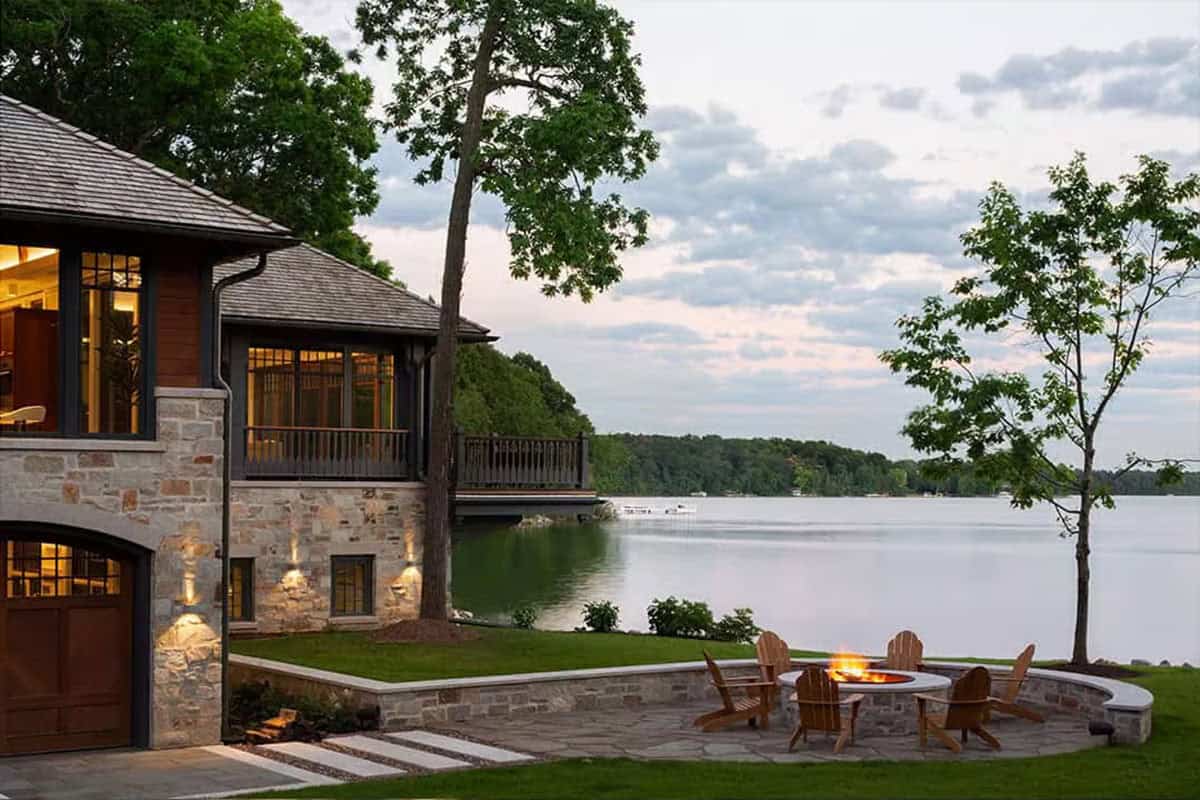 Stone fire pit with Adirondack chairs beside the boathouse at dusk