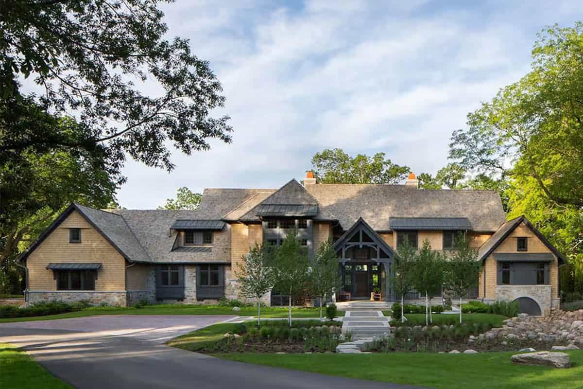 Shingle-style lake house with gabled entry porch and young birch trees