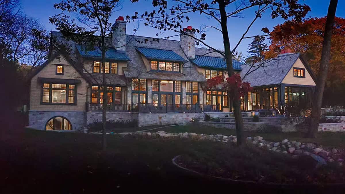 Lake house exterior lit up at night among autumn trees