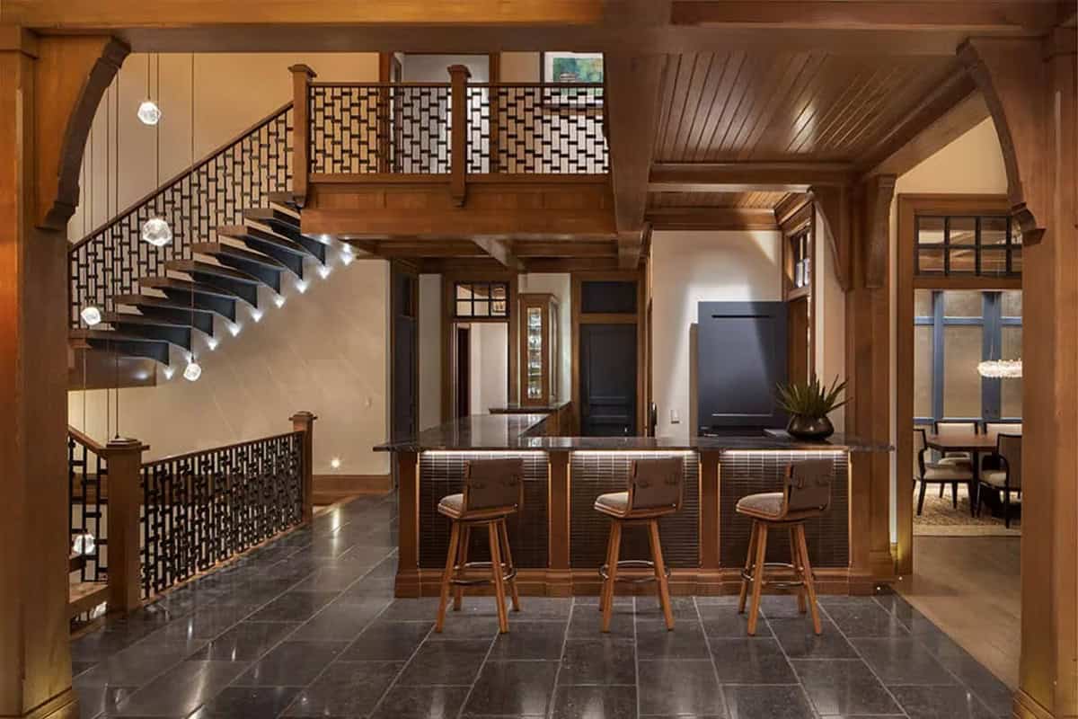 Home bar with leather stools beside floating stairs with lit treads