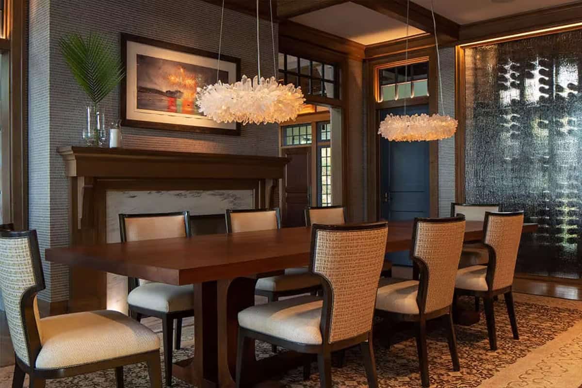 Dining table with woven chairs, crystal chandeliers and backlit glass wine wall