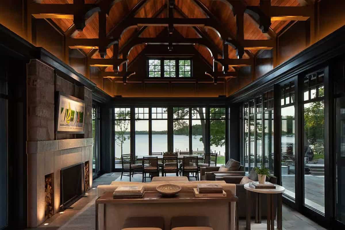 Lake pavilion with dark timber trusses, stone fireplace and lake view