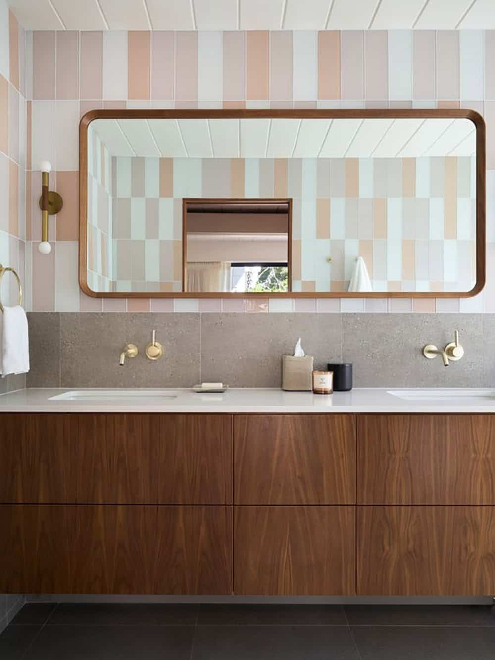 Walnut floating double vanity with wall-mounted brass faucets, a walnut-framed mirror and stacked blush, mint and gray tile