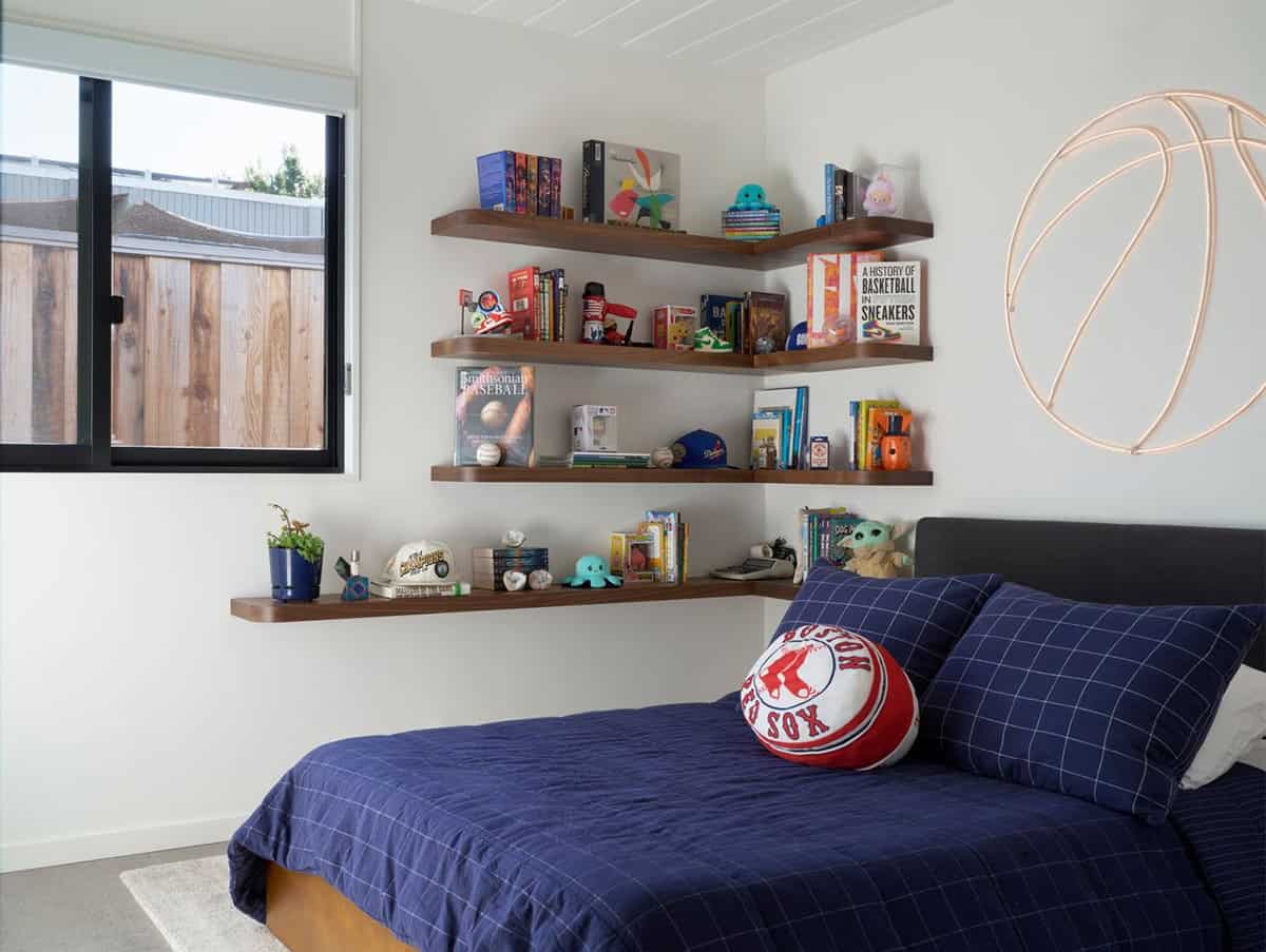 Kid's bedroom with walnut corner floating shelves of books and sports collectibles, a neon basketball wall light and navy plaid bedding