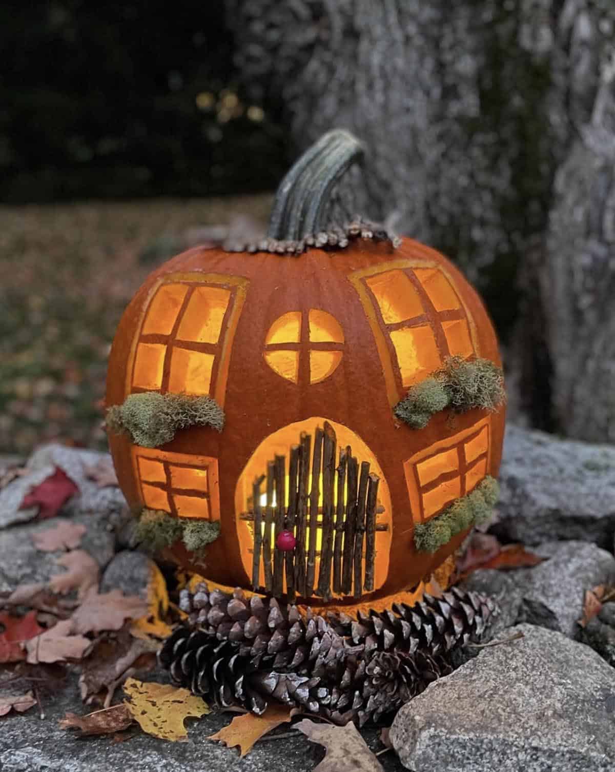 glowing jack-o'-lantern with twig door, carved windows, and moss window boxes