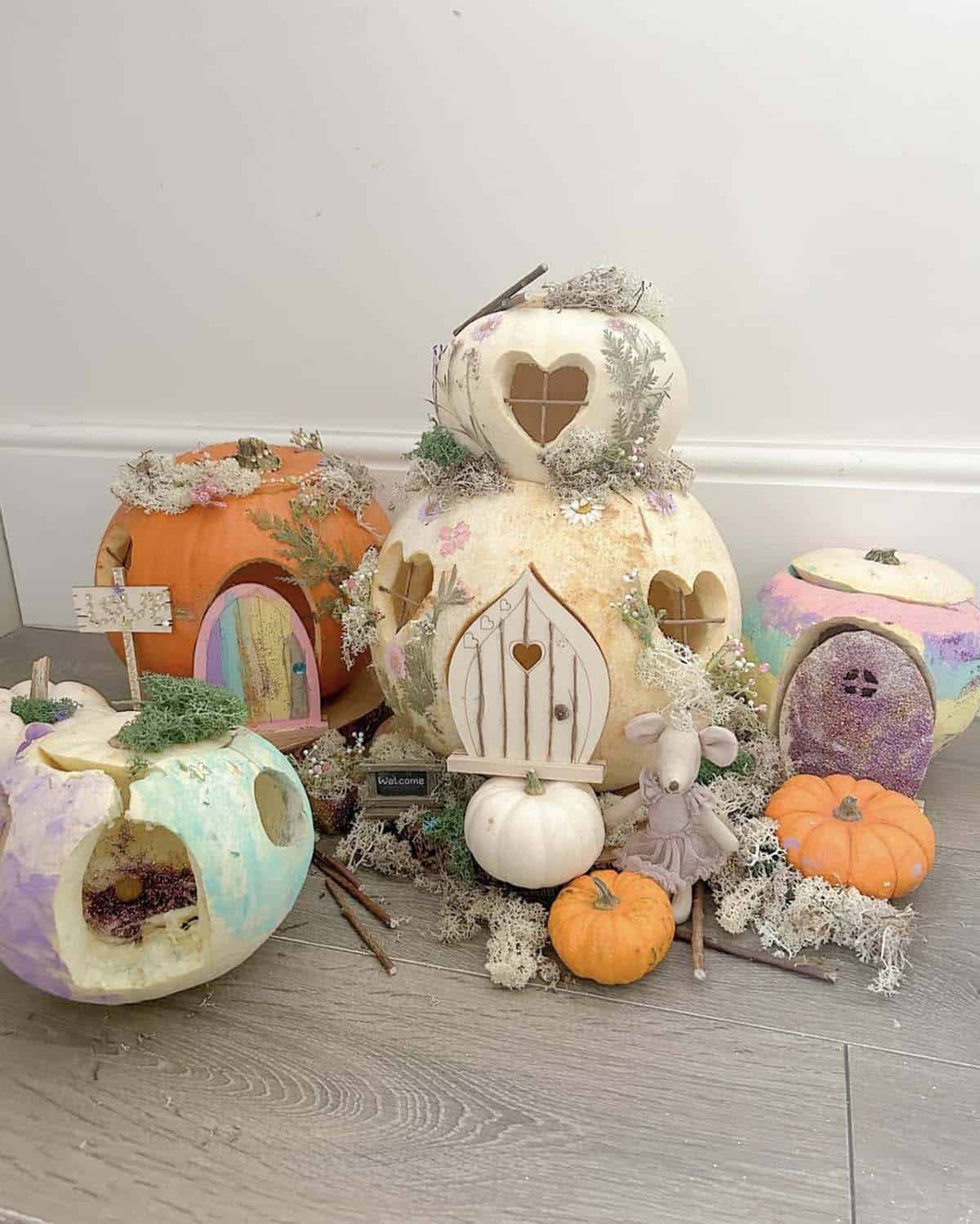 fairy village of pastel painted jack-o'-lanterns with glitter doors, pressed flowers, and a toy mouse