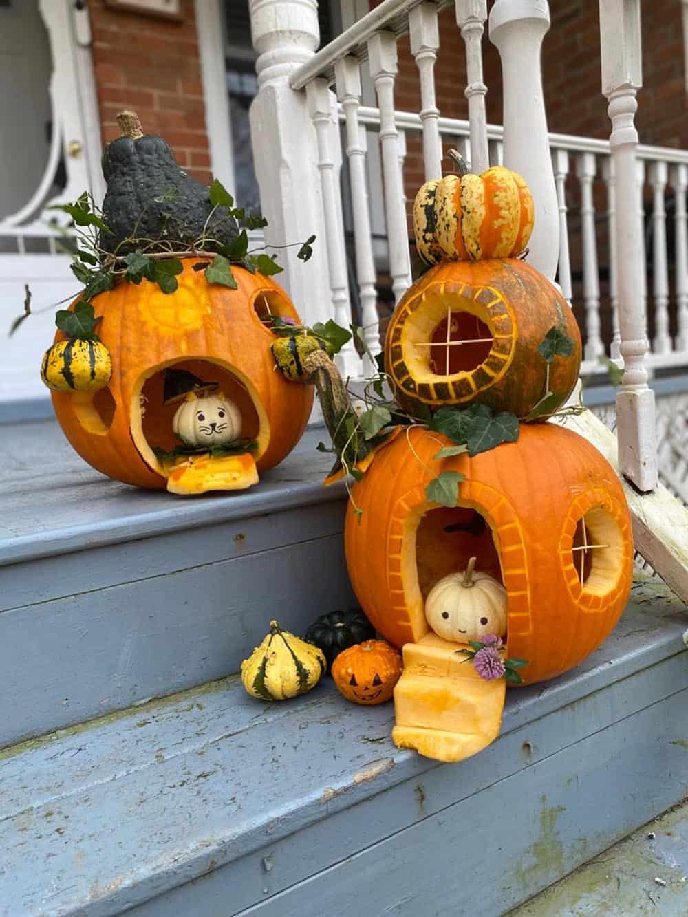 fairy house pumpkins with arched doors, twig windows, and ivy on porch steps