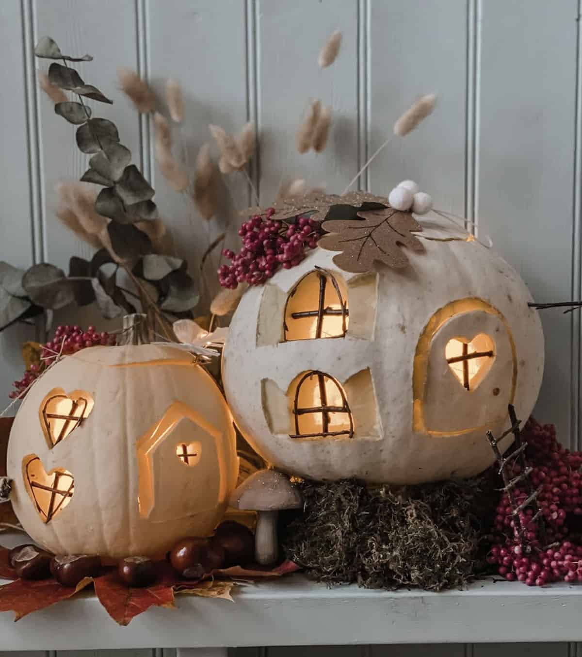 glowing white jack-o'-lanterns with arched and heart-shaped windows, twig panes, paper oak leaves, and pink berries