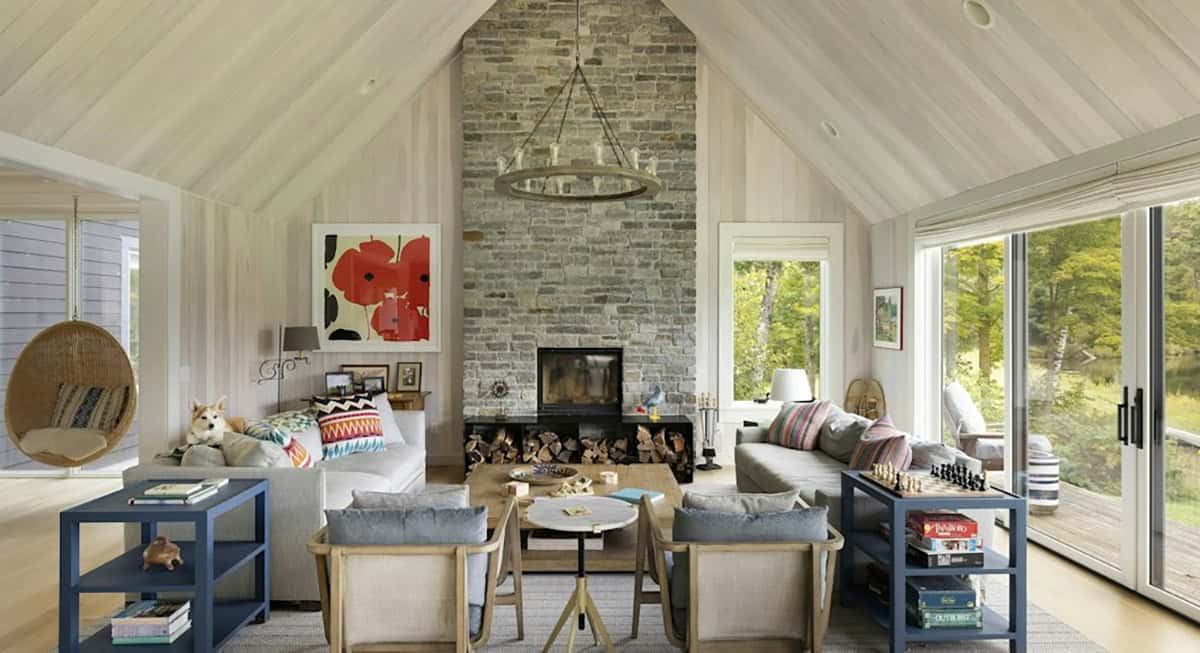 Family room with a floor-to-ceiling stone fireplace, a red poppy print, gray sofas, blue side tables and a corgi on the sofa