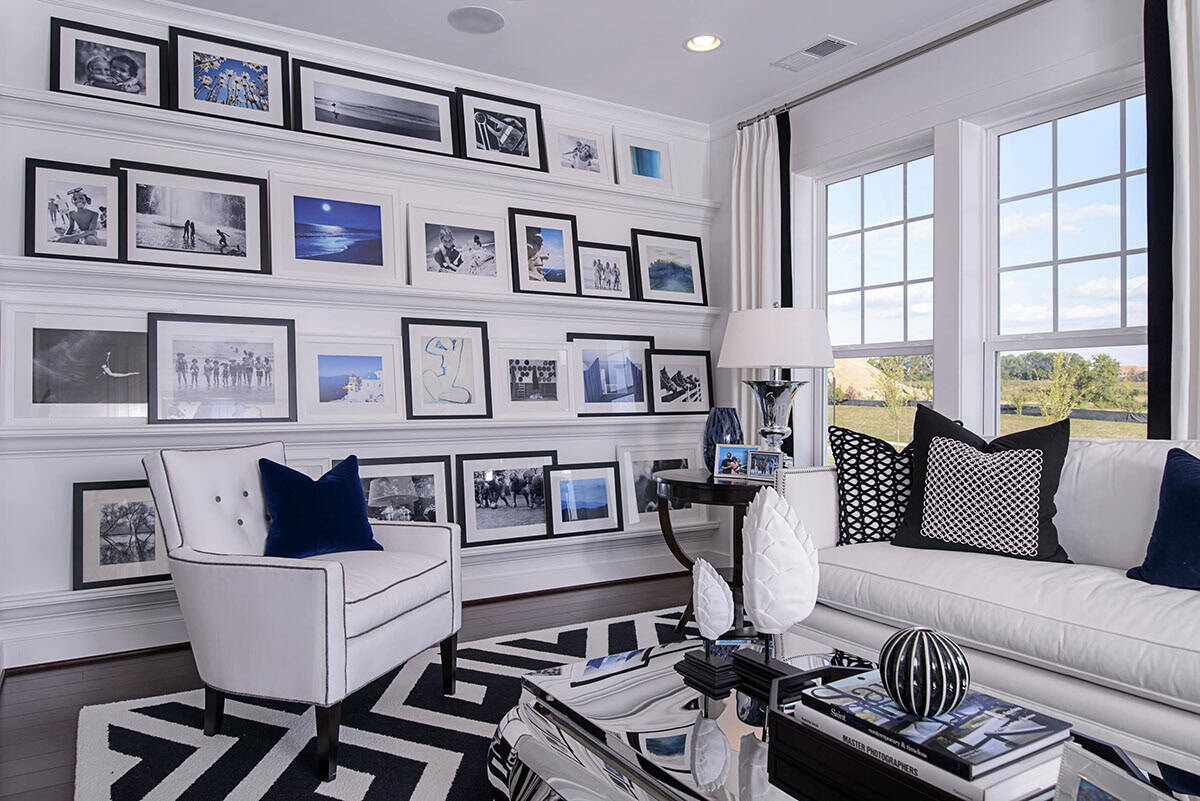 Living room wall of white picture ledges lined with black and white framed photographs
