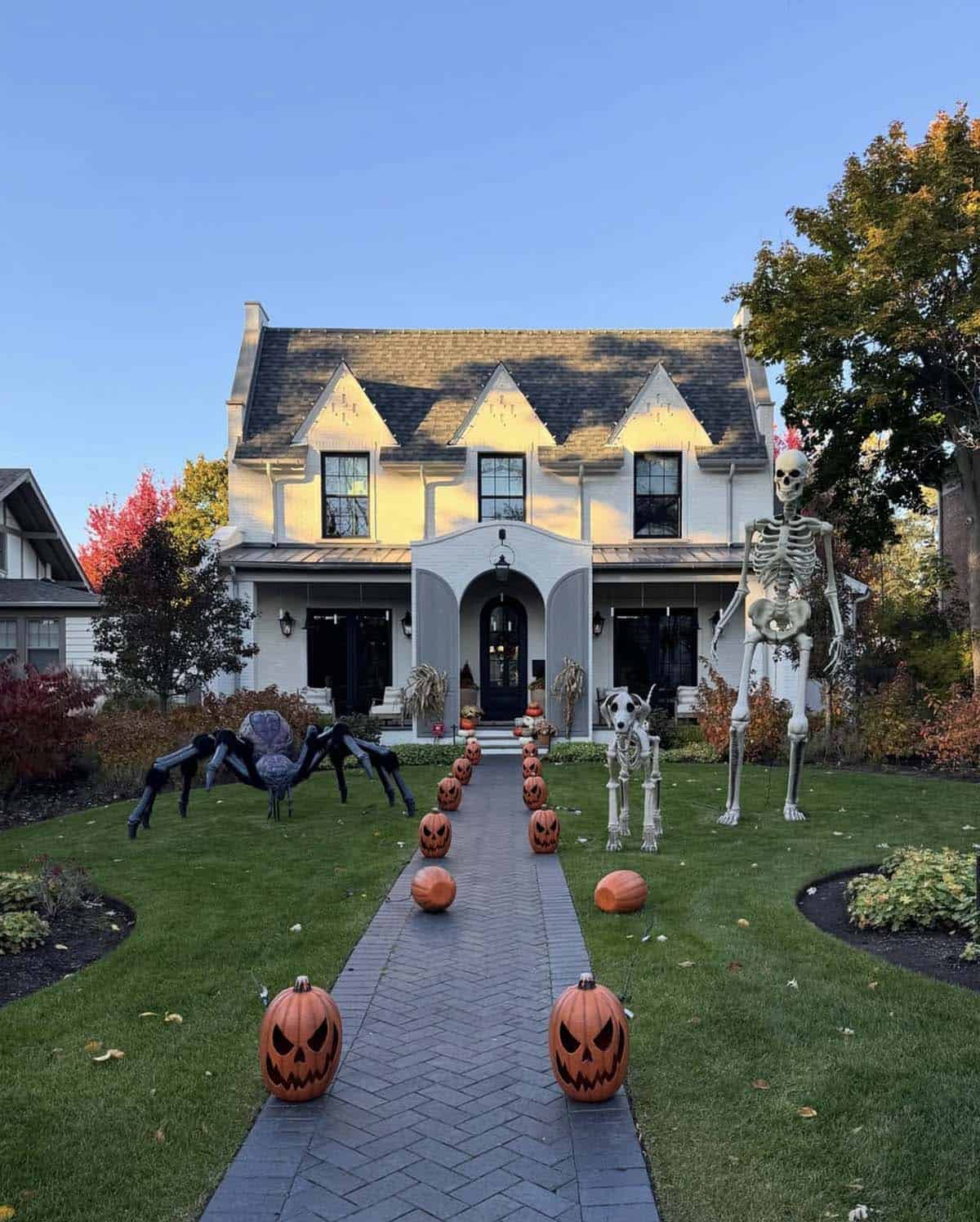 Giant skeleton, skeleton dog, and spider with jack-o'-lantern pathway in a Halloween front yard decoration idea
