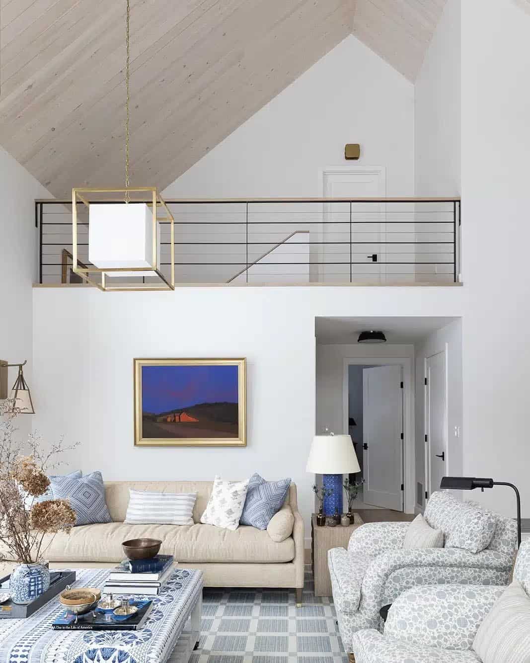 Vaulted living room with a loft railing, brass cube pendant and blue-and-white furnishings