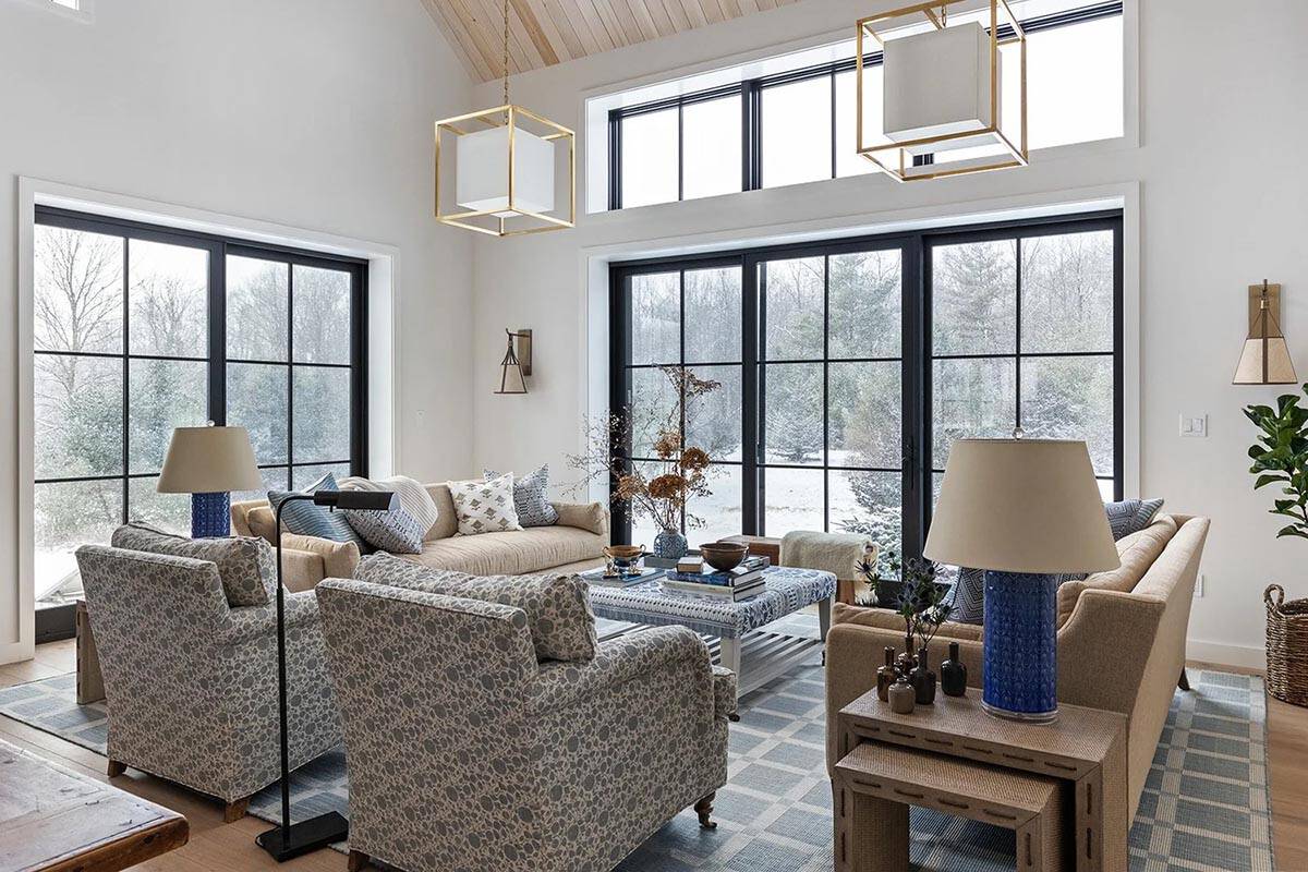 Living area with patterned armchairs, blue ceramic lamps and floor-to-ceiling windows in winter