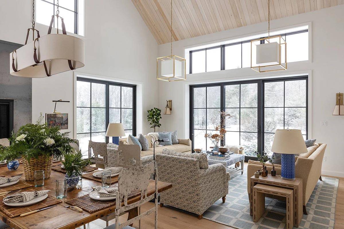 Open-plan dining and living space under a pale wood vaulted ceiling with brass pendants