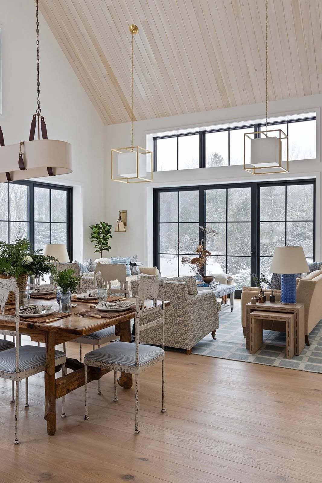 Rustic dining table with metal cow-motif chairs beside the living area and high windows