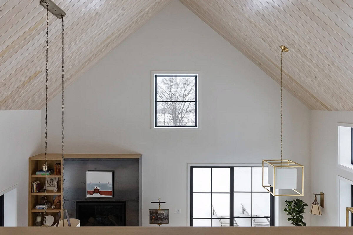 View from the loft to a steel fireplace surround and vaulted ceiling with a single gable window