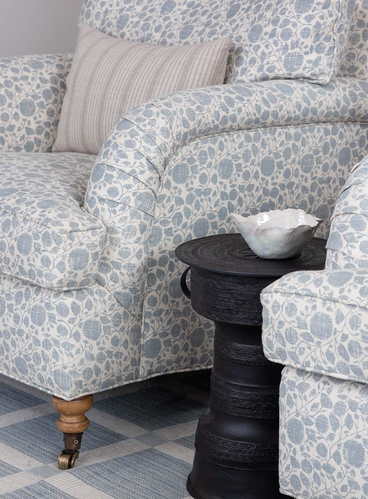 Blue floral armchairs with a black carved side table and a checked rug