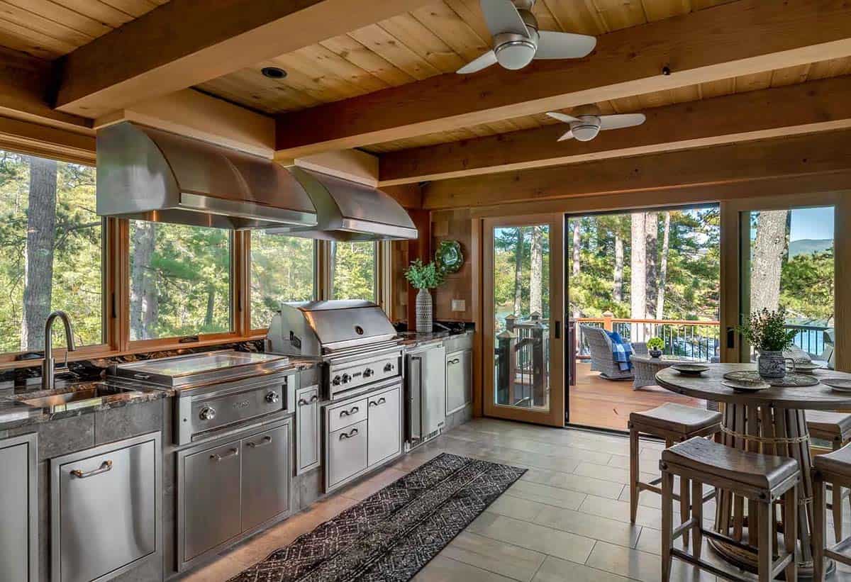 Indoor grilling kitchen with stainless steel grills, beamed ceiling, and sliding doors to the deck