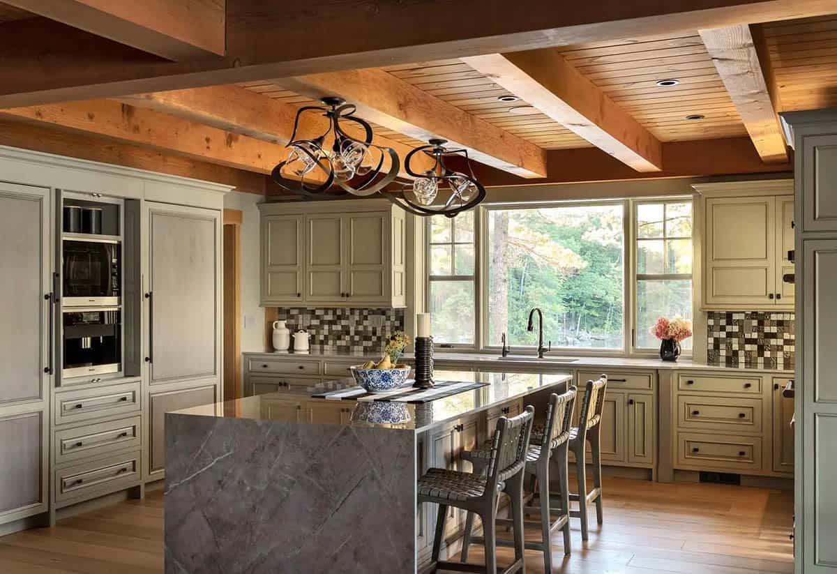 Kitchen with sage green cabinetry, waterfall stone island, and exposed wood ceiling beams