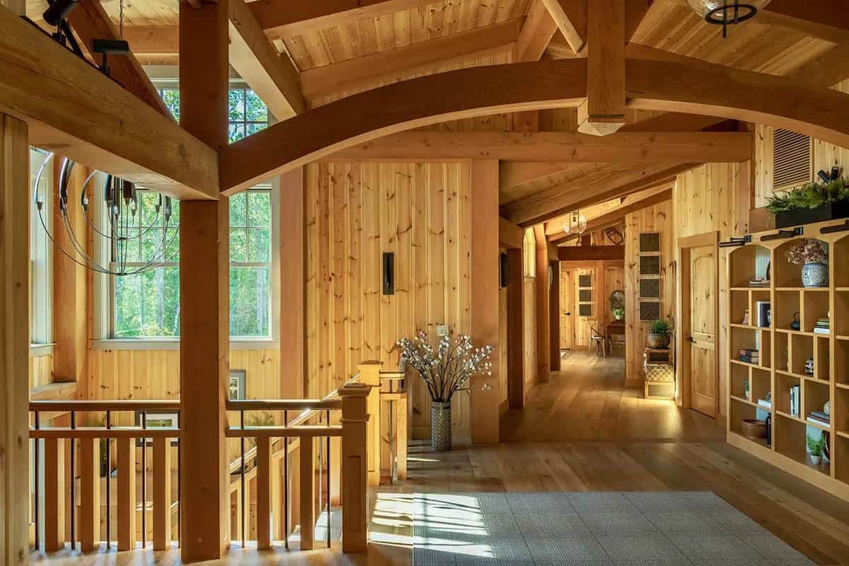 Upper hallway with curved timber trusses, pine-paneled walls, and built-in bookshelves