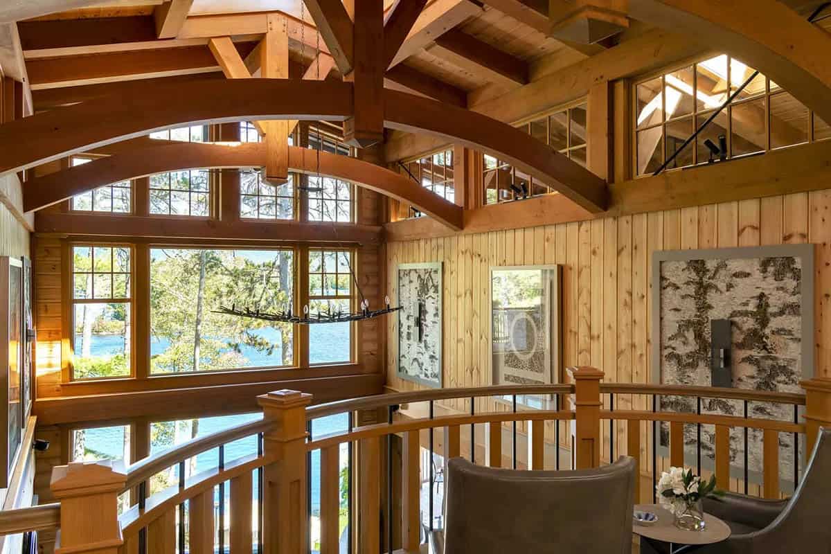 Second-floor landing with arched timber trusses and windows overlooking Lake Winnipesaukee
