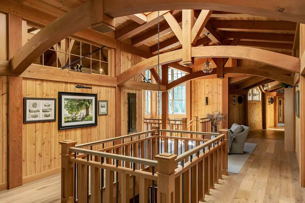Open balcony with curved timber beams, wood railing, and framed artwork on pine walls