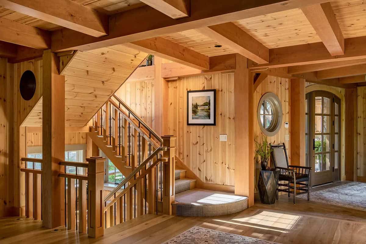 Foyer with timber frame ceiling, open staircase, and round porthole window