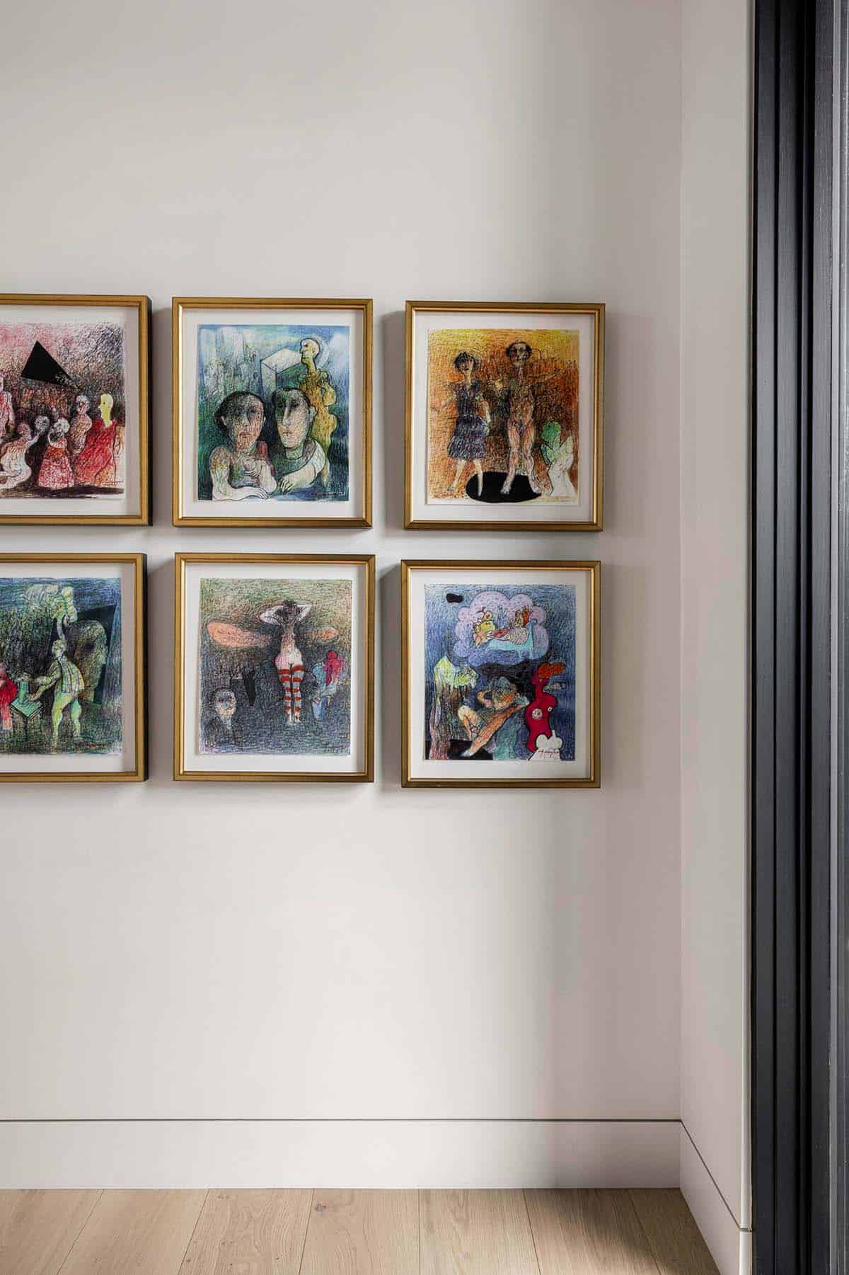 Gallery wall of colorful figurative drawings in gold frames