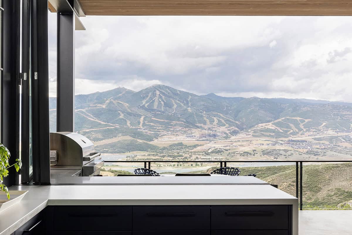 Bifold kitchen window folded open to covered terrace with built-in grill