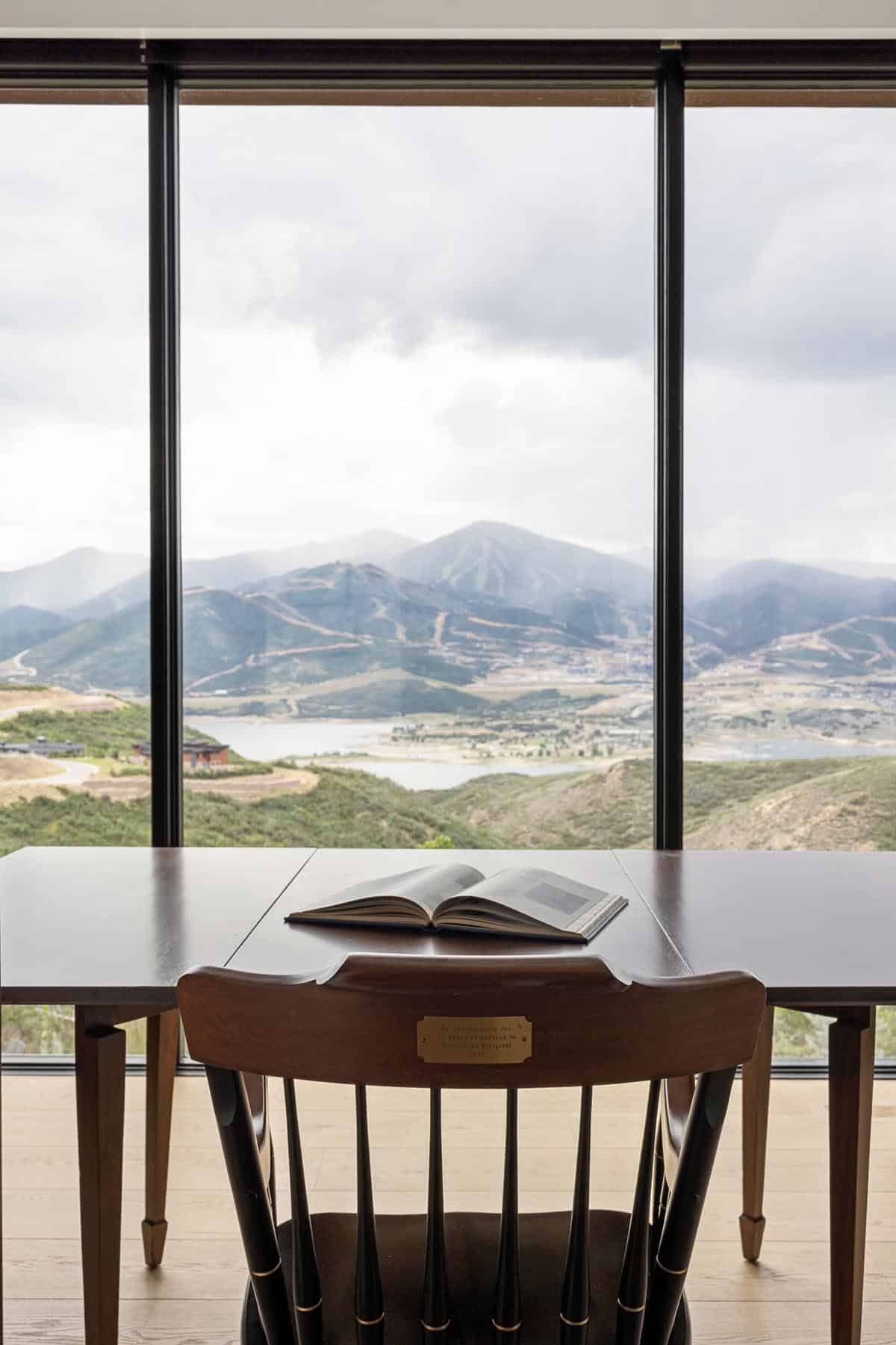 Antique writing table and Windsor chair facing window with lake and mountain view