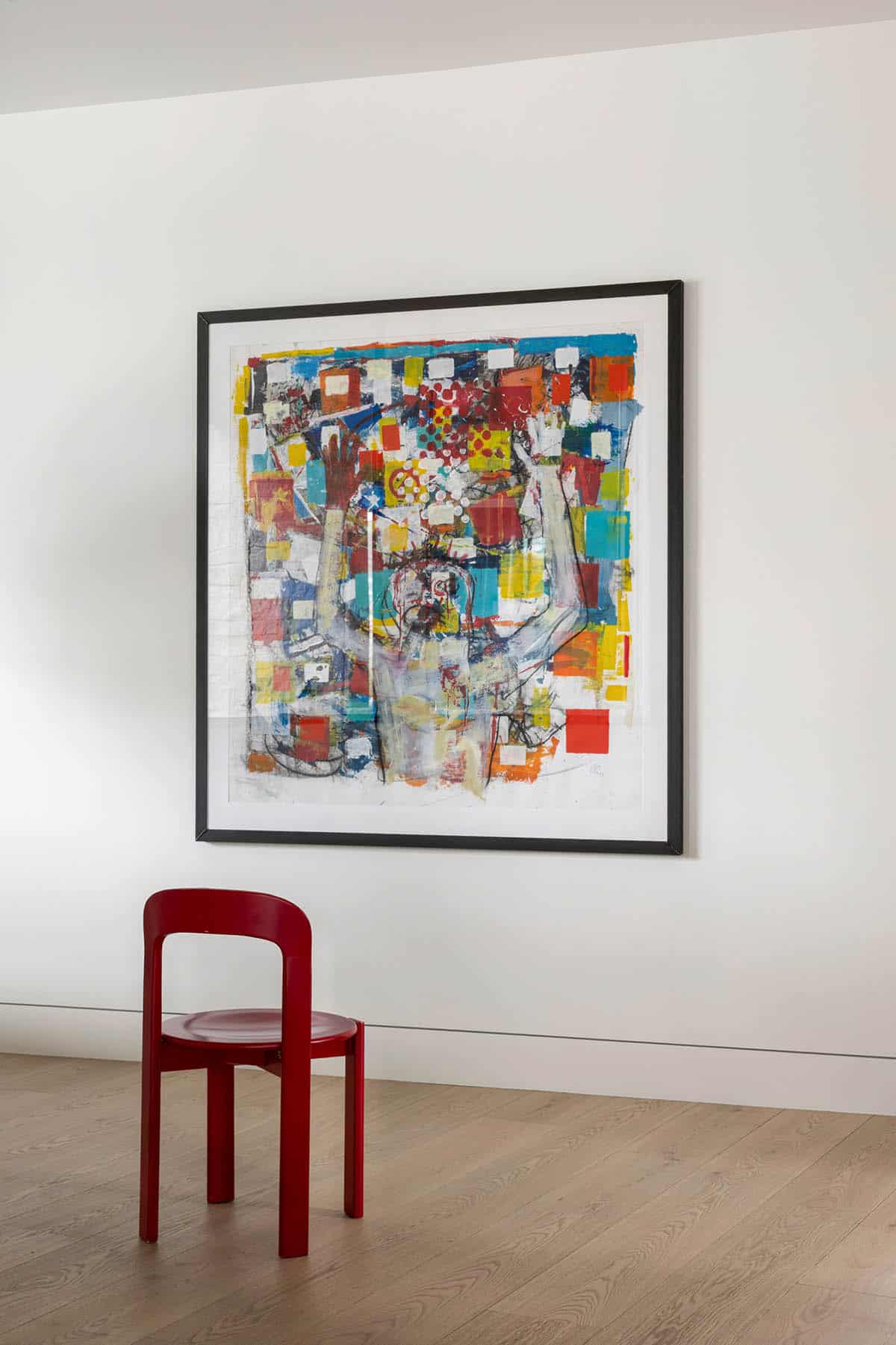 Large colorful abstract painting above red wood chair