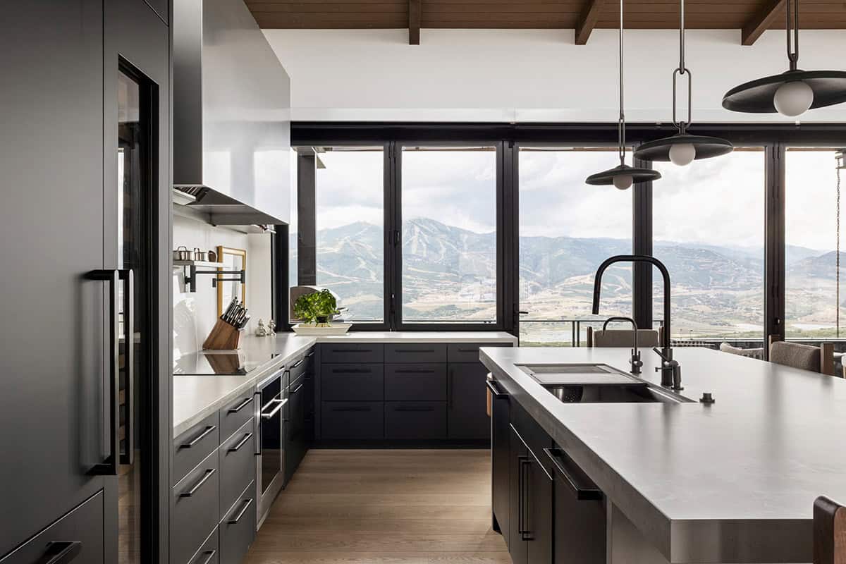 Kitchen with black cabinetry, gray island, and window wall facing ski slopes