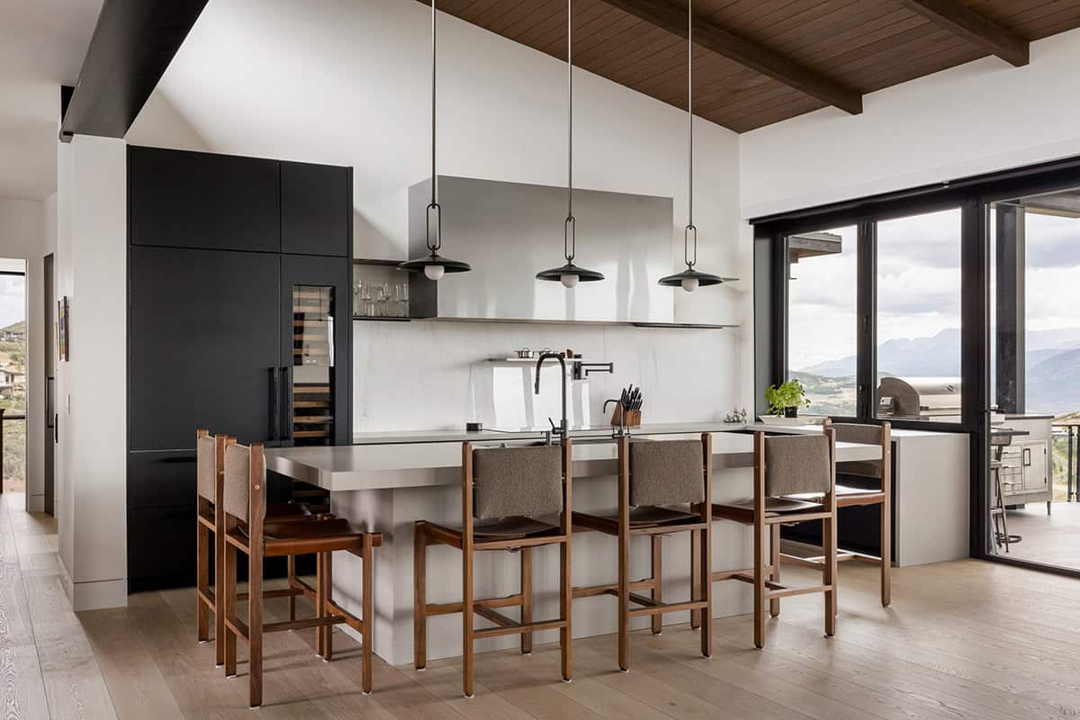 Kitchen with built-in wine fridge, gray island, and walnut and leather counter stools