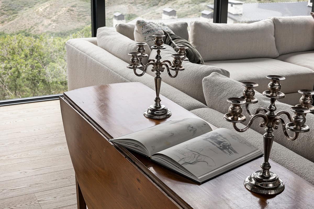 Silver candelabras and open sketchbook on antique drop-leaf table behind sofa