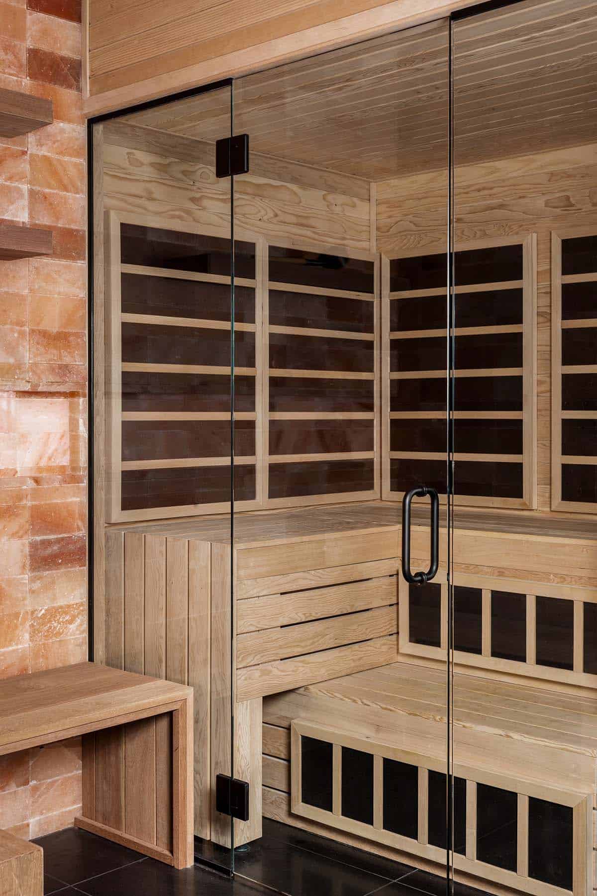 Wood sauna with glass door beside Himalayan salt block wall