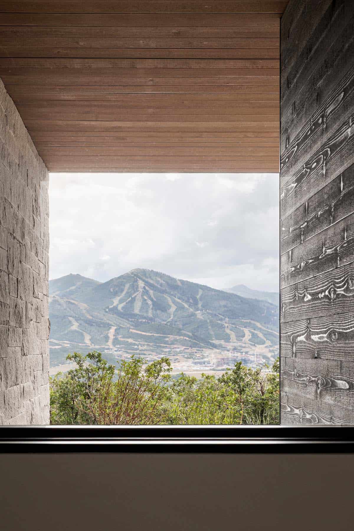 Window framing ski mountain between stone and dark wood walls