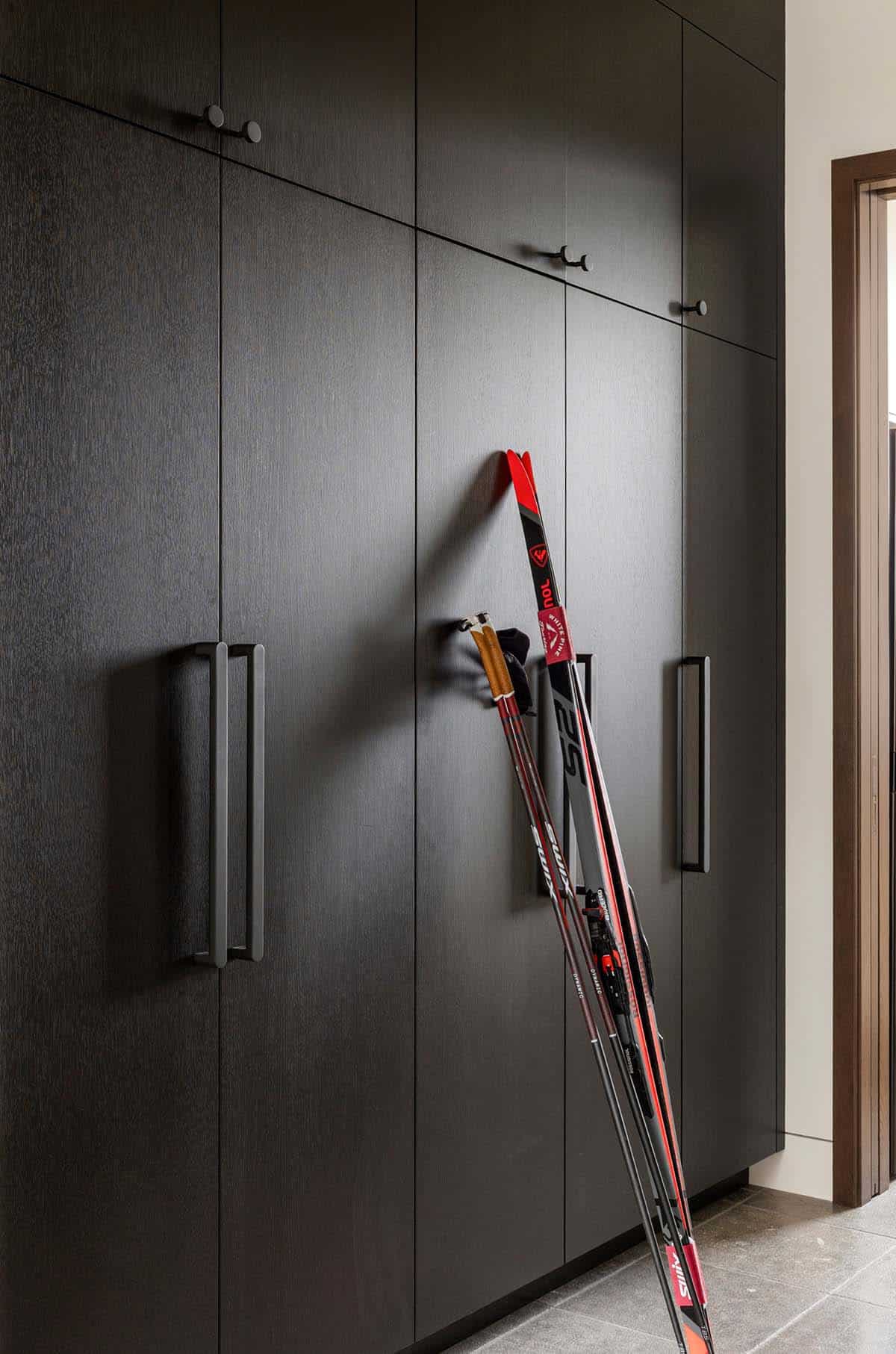 Dark oak mudroom cabinets with cross-country skis leaning against them