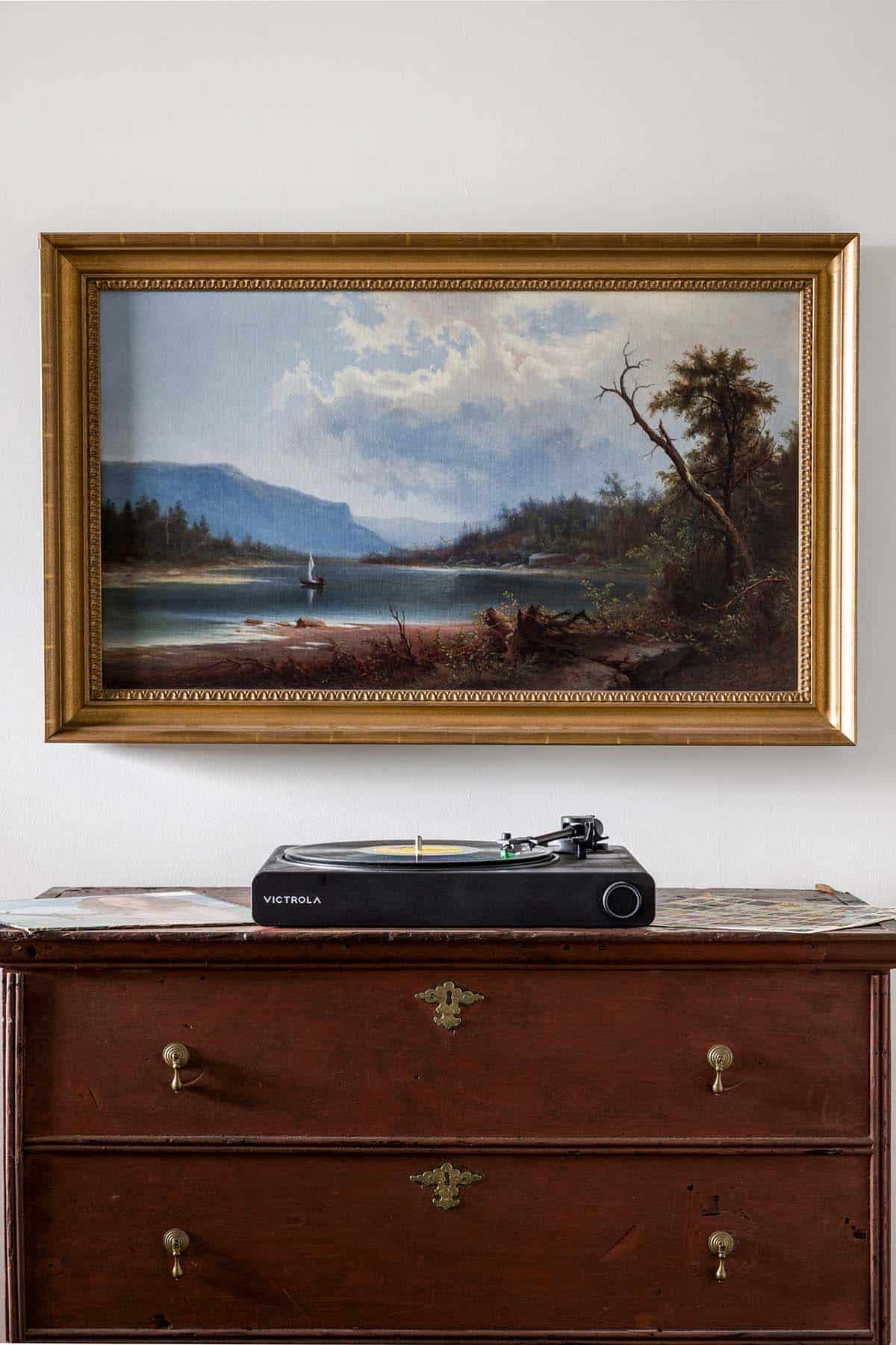 Landscape painting in gilded frame above antique chest with record player