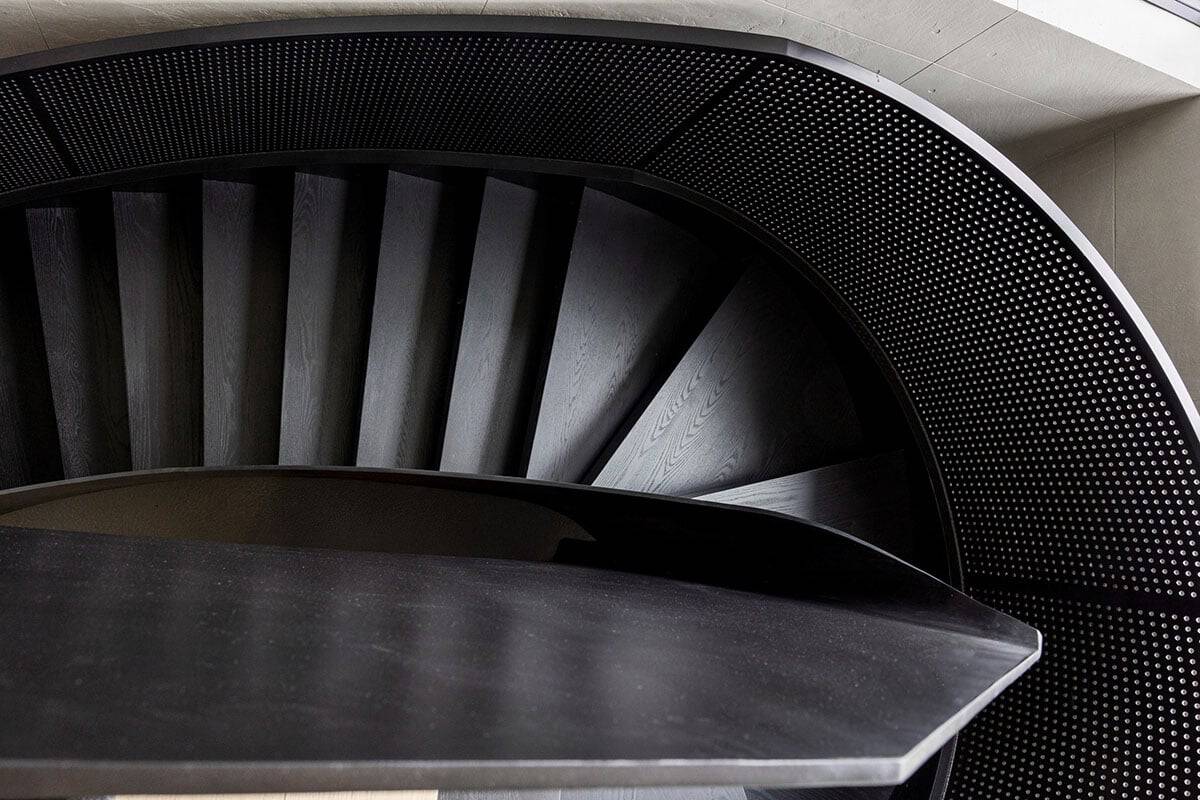 Overhead view of black oak spiral staircase with perforated steel railing
