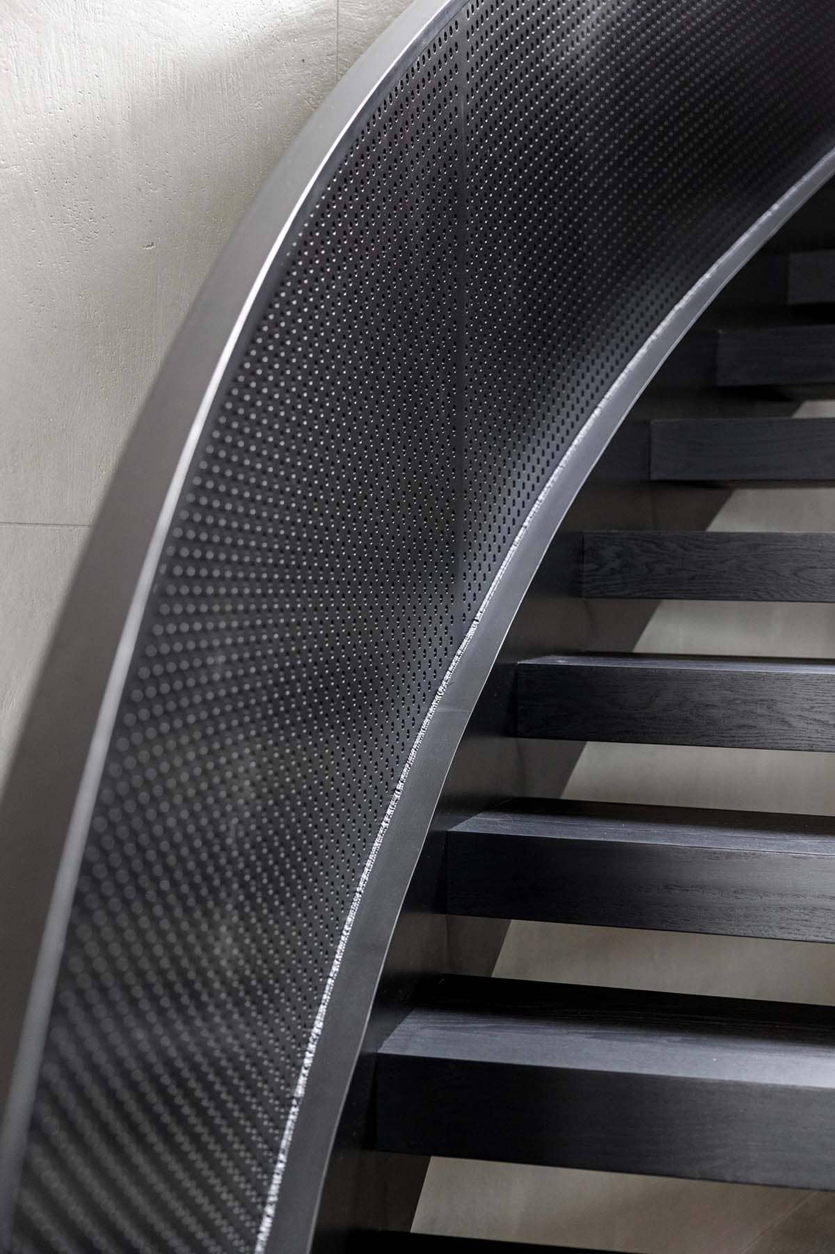Curved perforated steel stair railing with black oak treads