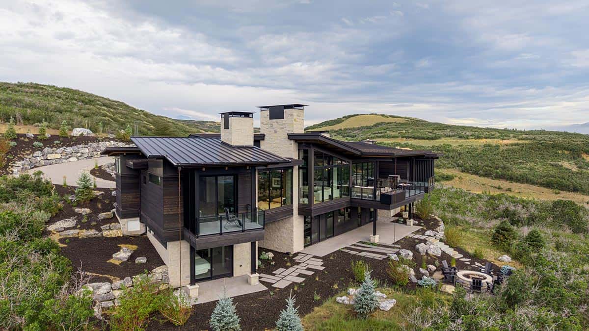 Aerial view of rear terraces, stone paths, and fire pit below the home