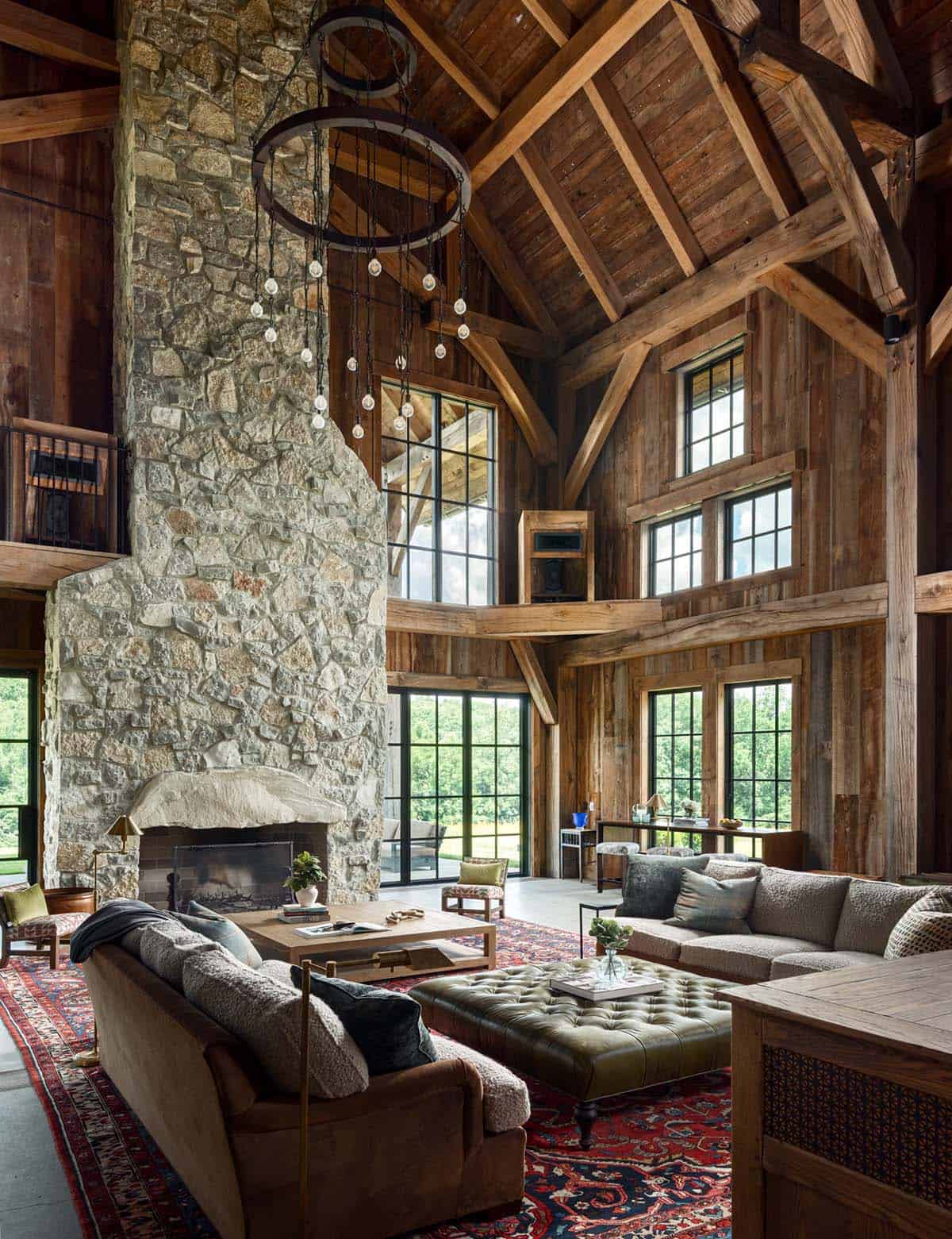 Great room with stone fireplace, ring chandelier, and timber trusses