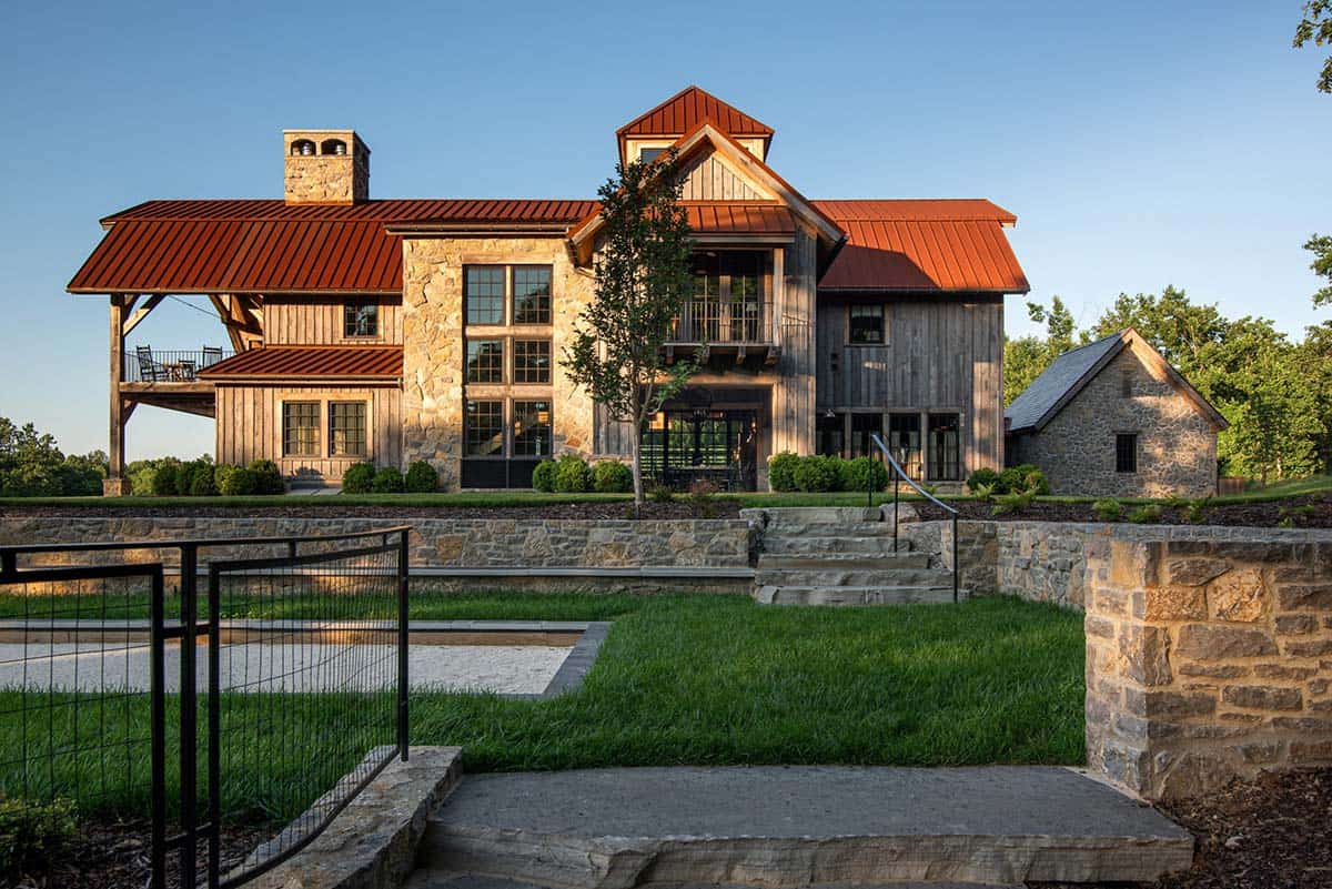 Stone steps and terraced lawn leading up to reclaimed wood home