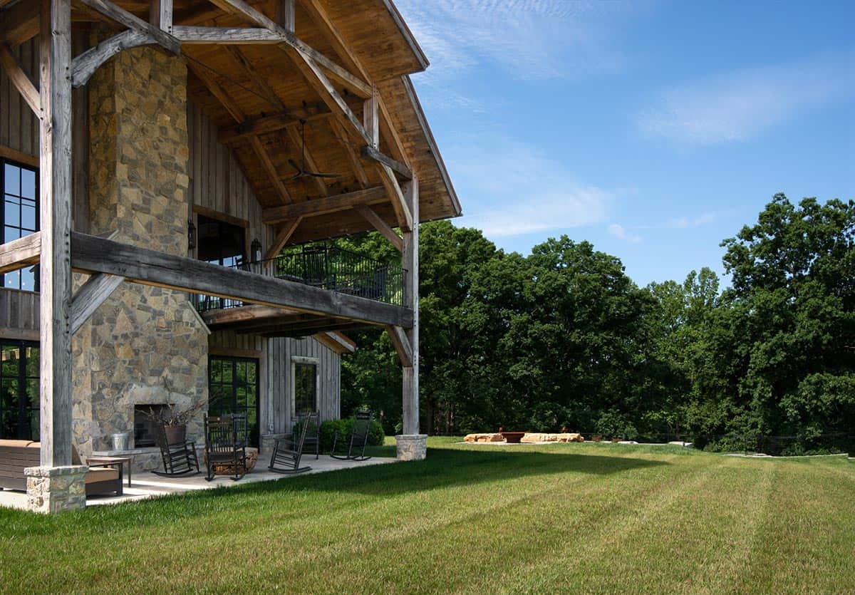 Covered porch with outdoor fireplace and rocking chairs facing lawn