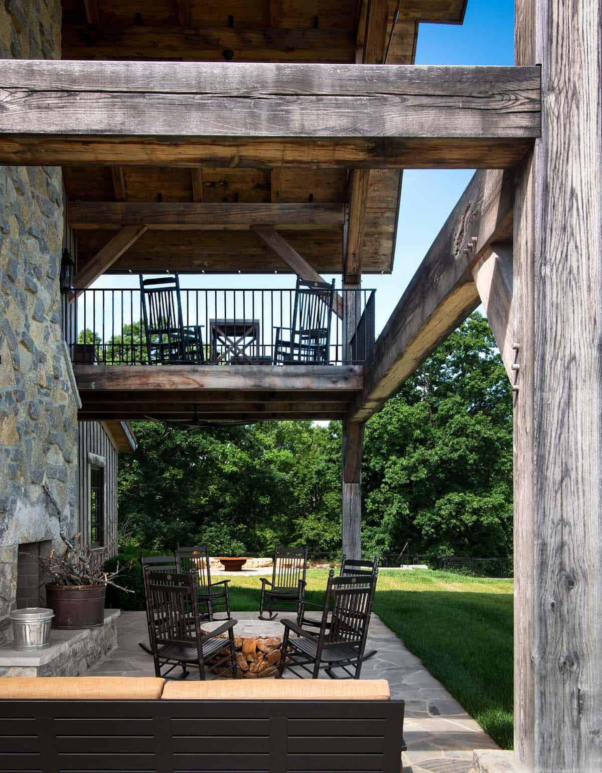 Rocking chairs around a fire pit under timber-frame balcony
